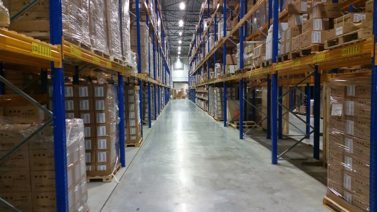Pasillo de racks cargados con tarimas apoyados sobre el piso industrial