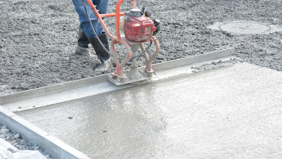 Cuadrilla enrasando con regla vibratoria el colado de un piso industrial