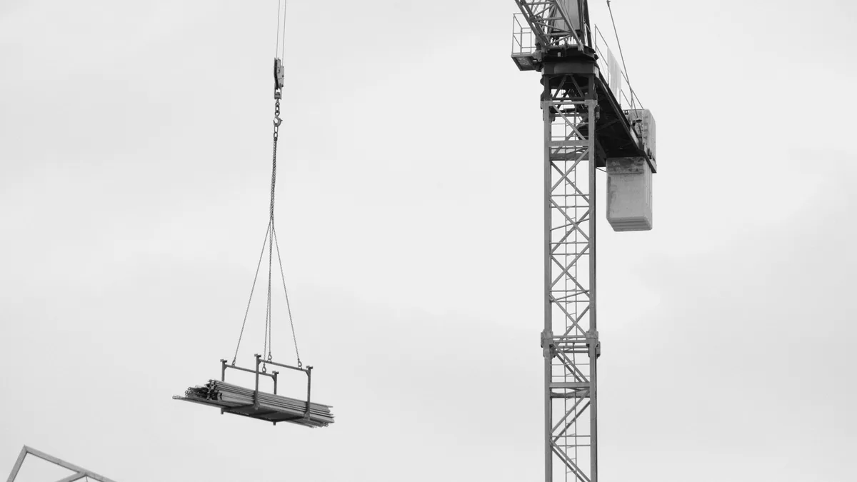 Grúa izando un elemento estructural durante el montaje de una bodega