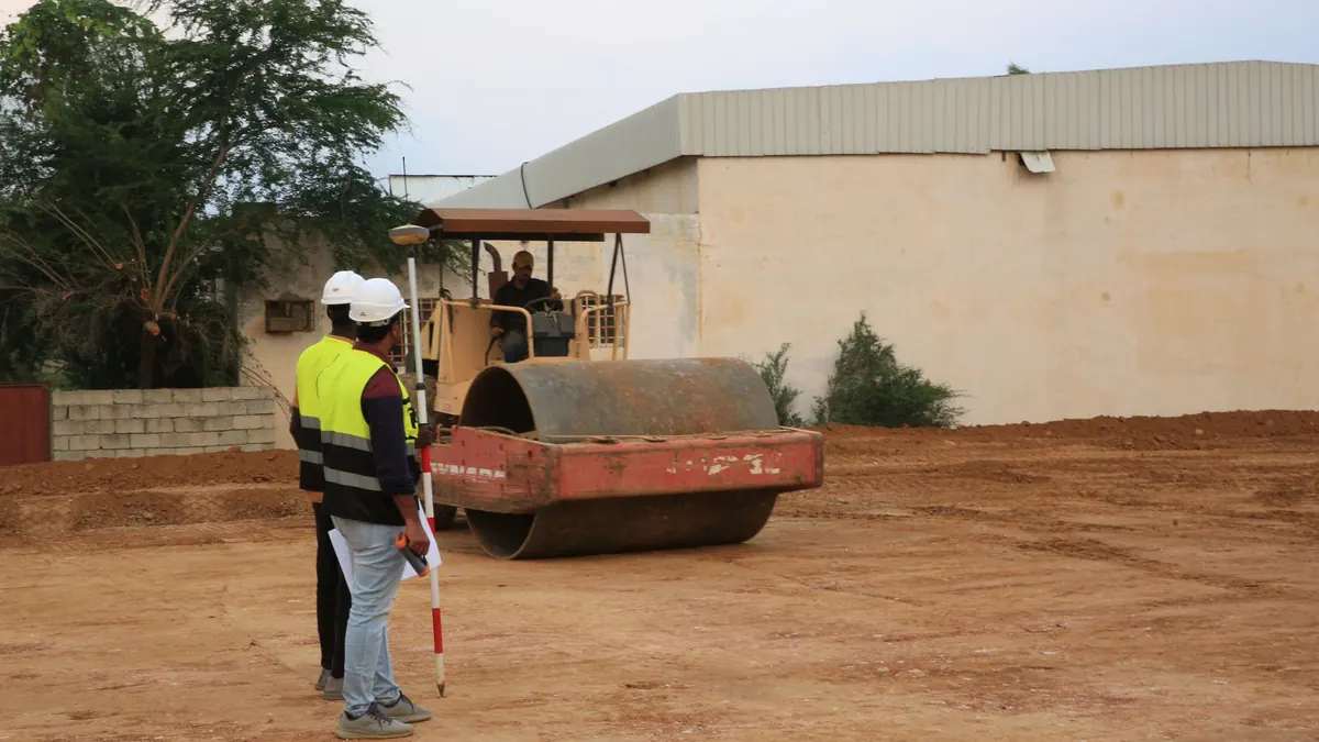 Trazo y nivelación con estadal junto al rodillo que compacta la plataforma